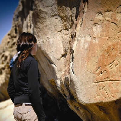 A person in a black, long-sleeve sweater looks at the petroglyphs at White Mountain near Rock Springs, Wyoming.