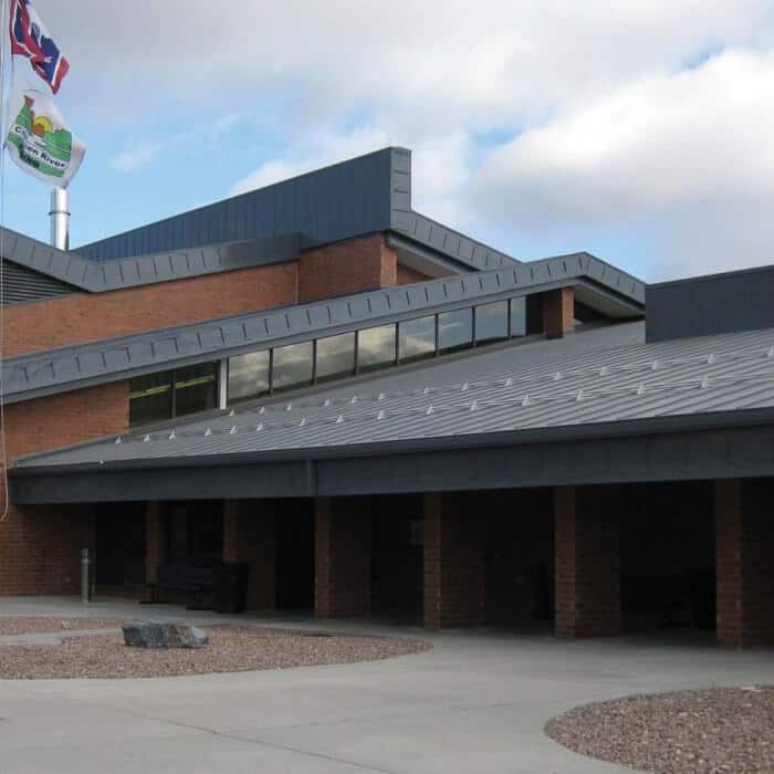 A brick and metal building with large windows and two flags outside, set under a cloudy sky.