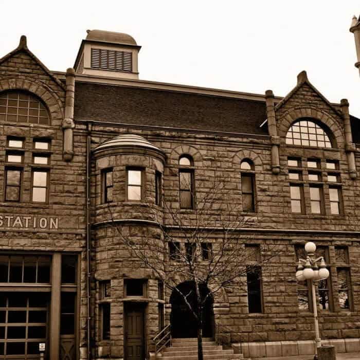 A historic stone building with arched windows, a turret, and a visible sign reading "STATION" on the left side.