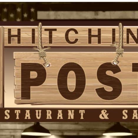 A wooden sign reads "Hitching Post Restaurant & Saloon" with rope details and an American flag partially visible in the background.
