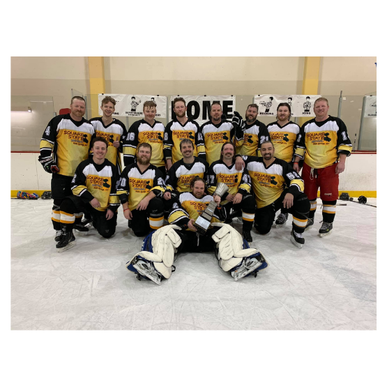 A hockey team in matching yellow and black jerseys poses on the ice with a trophy.